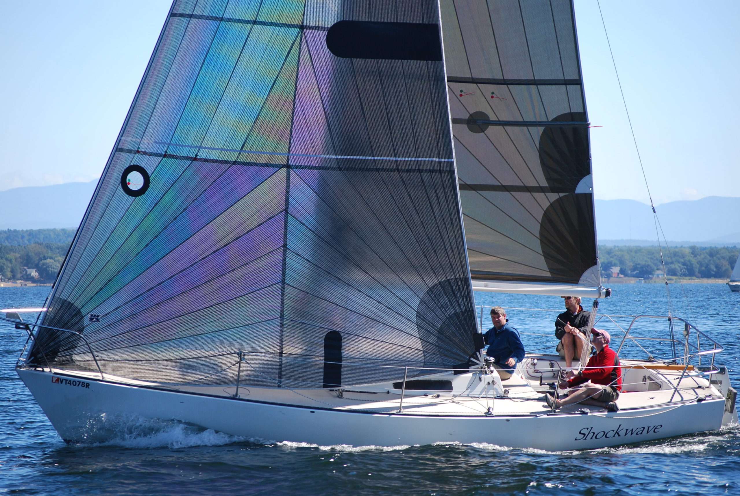 3 people in a sailboat on the lake